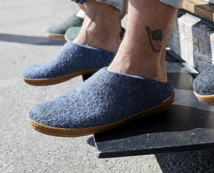 A close up picture of a person wearing glerups slip-ons in the color Denim with natural rubber sole. 